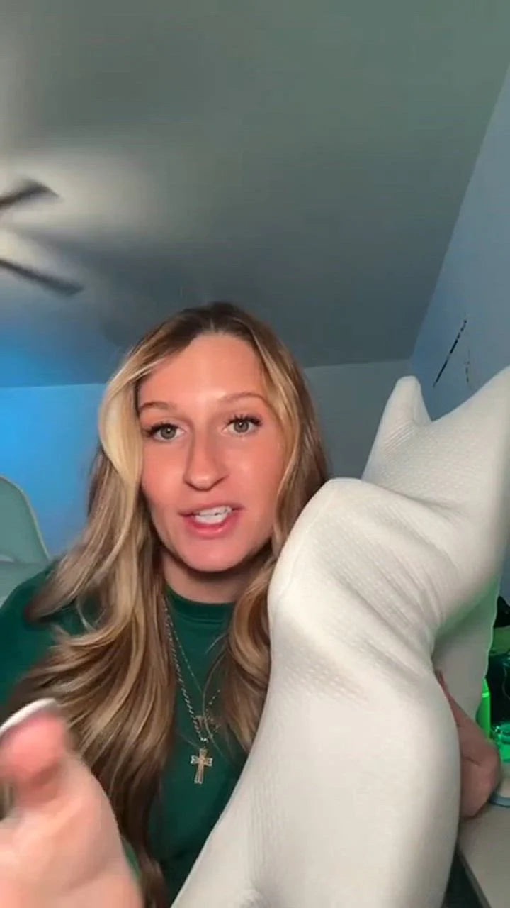 Kundenreview-Video-Still von Frau mit ergonomischem Nackenkissen, zeigt Freude und Komfort bei Nackenunterstützung für entspannten Schlaf.